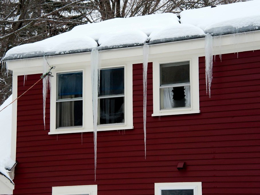 Roofline with ice dams and icicles before a maintenance visit